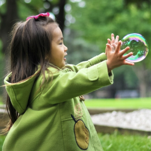 Little girl reaching out to grab a bubble